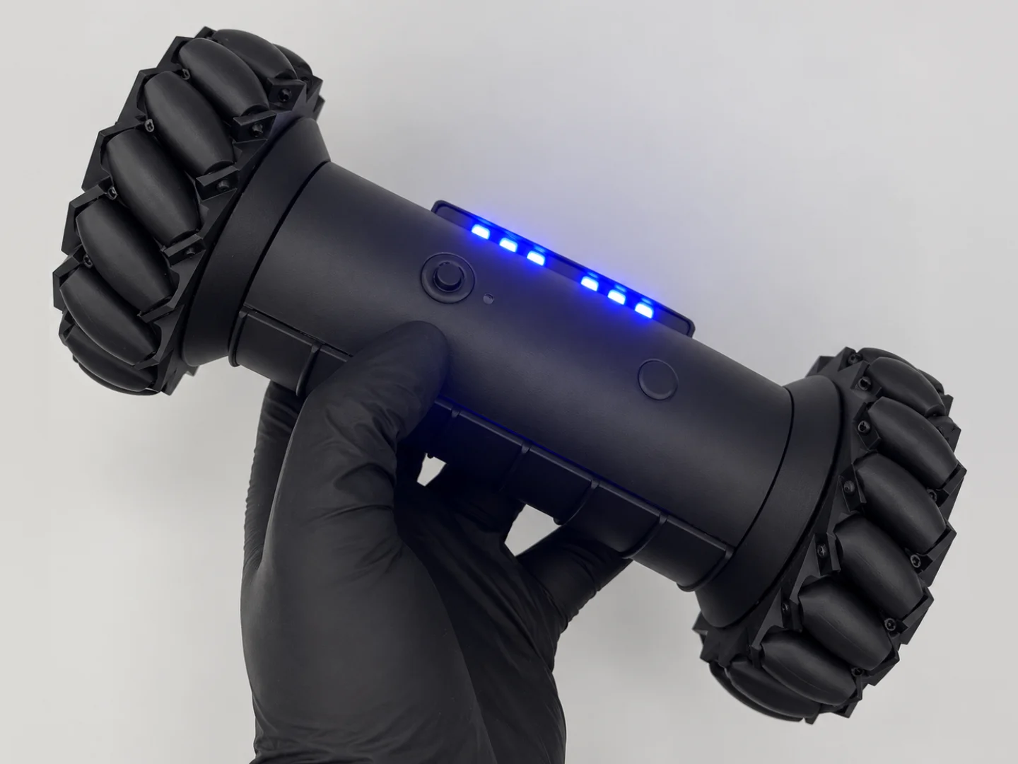 RCD-01 drone replica held in one gloved hand with its blue LEDs lit, to show its size